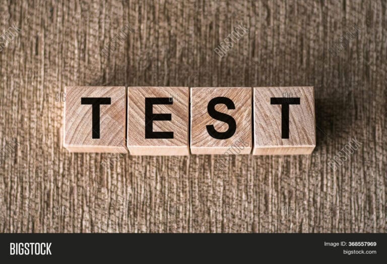 Wooden blocks arranged to spell the word 'TEST' on a textured surface.